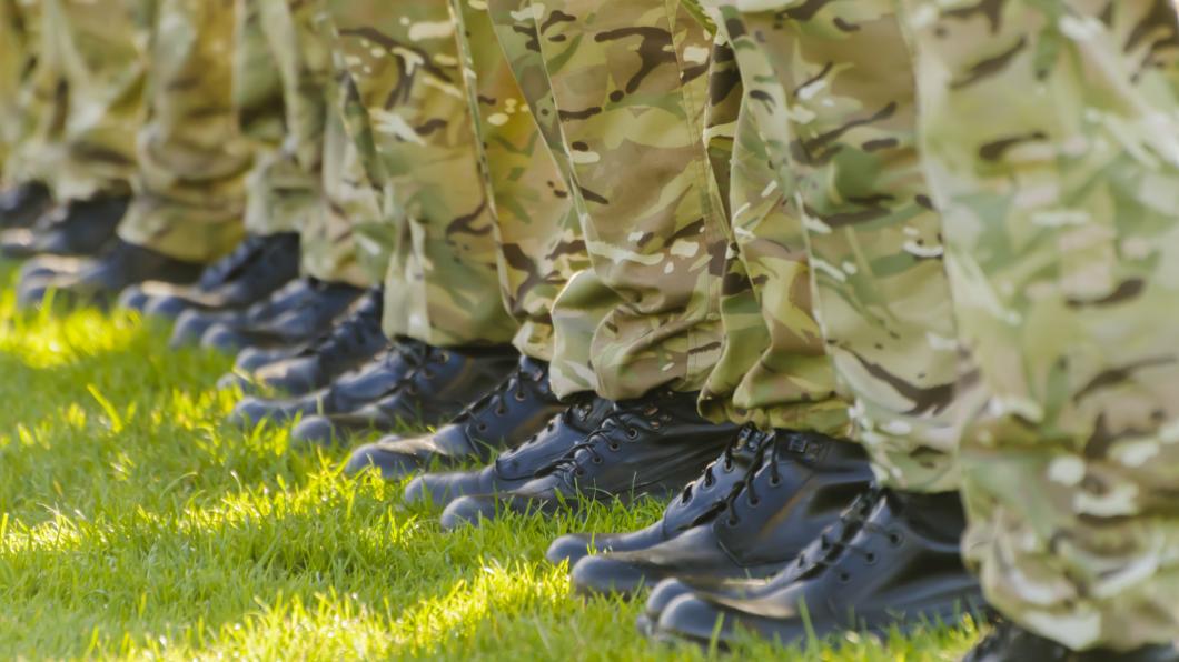 Soldaten staan op een rij met hun laarzen op een groen grasveld