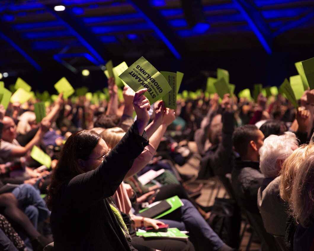 Leden houden op het congres de groene stemkaart omhoog om hun stem uit te brengen op een ingediende motie.