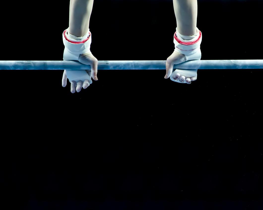 Close-up van handen van een turnster aan de rekstok