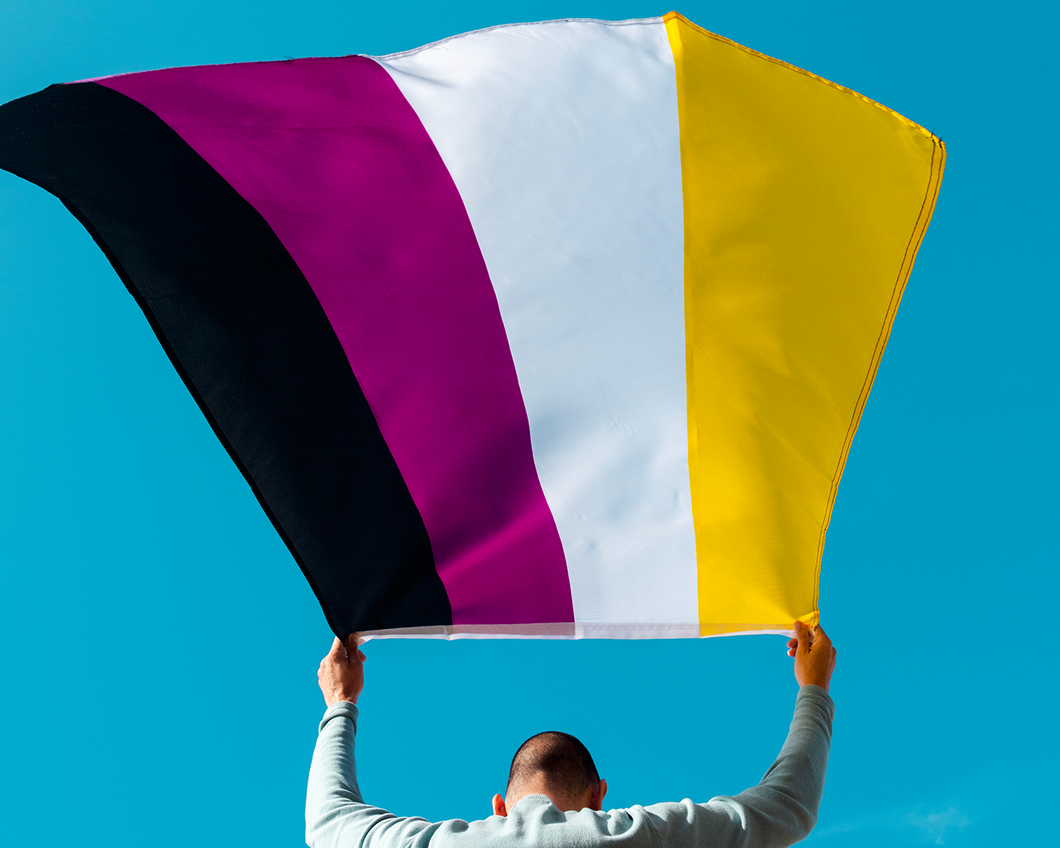 Een persoon houdt de non-binaire vlag vast