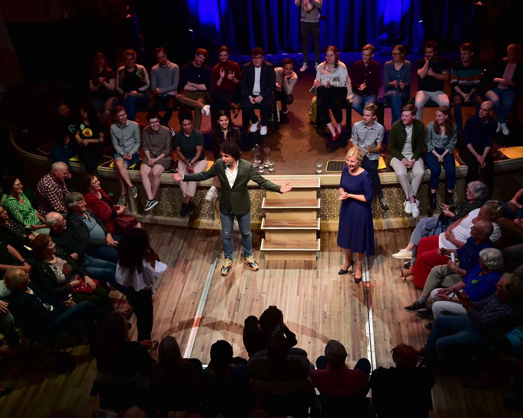 Jesse Klaver staat met gespreidde armen voor een publiek. Attje Kuijken staat naast hem naar hem te luisteren.