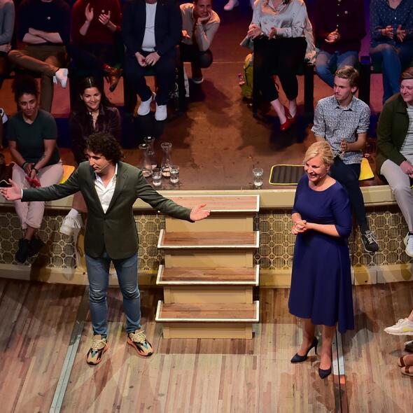 Jesse Klaver staat met gespreidde armen voor een publiek. Attje Kuijken staat naast hem naar hem te luisteren.