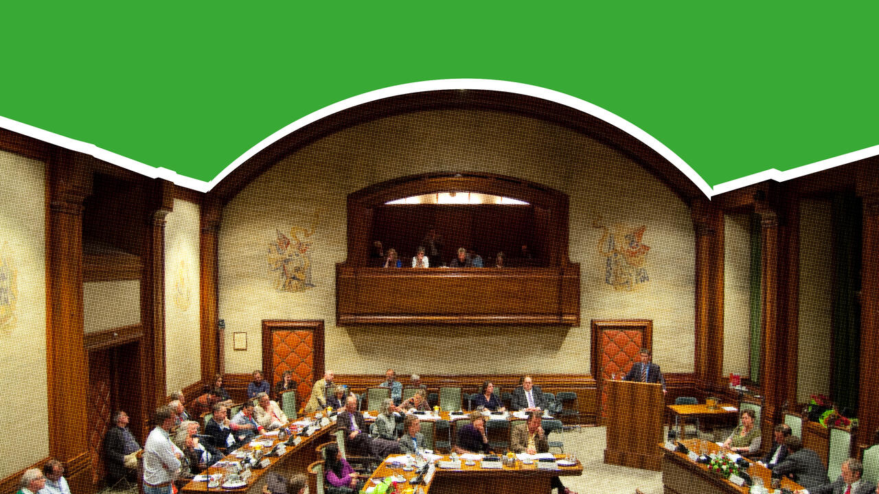 Een foto van een grote zaal met veel houten meubilair, gevuld met mensen